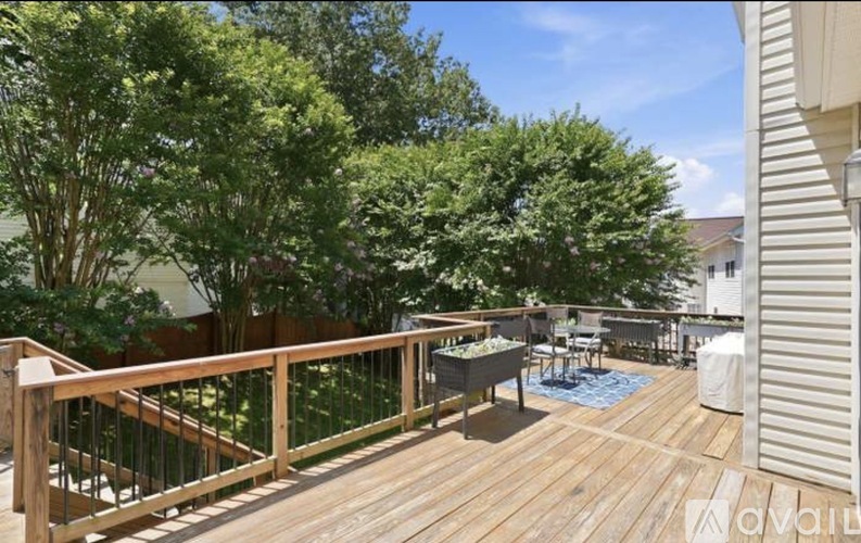 A wooden deck with a railing and a table surrounded by trees.