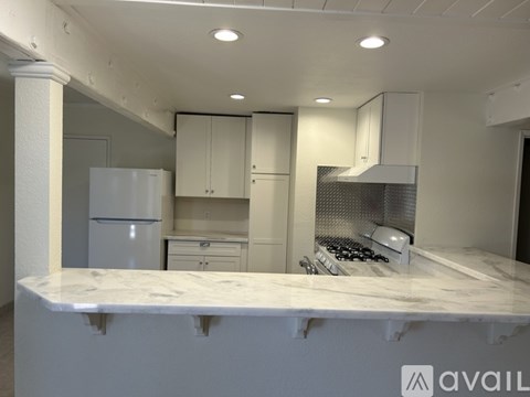 A kitchen with white cabinets and a marble countertop.
