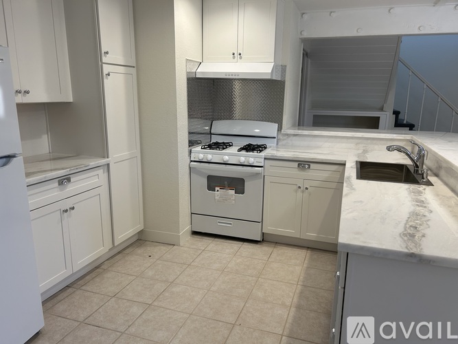 A kitchen with white cabinets and a stove top oven.
