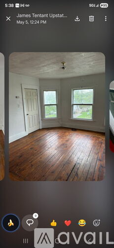 A room with wooden flooring and two windows.