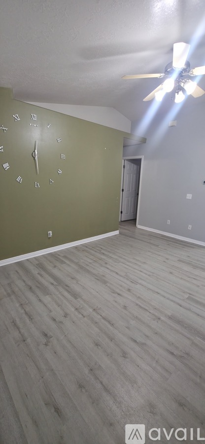 A room with a green wall and a wooden floor.