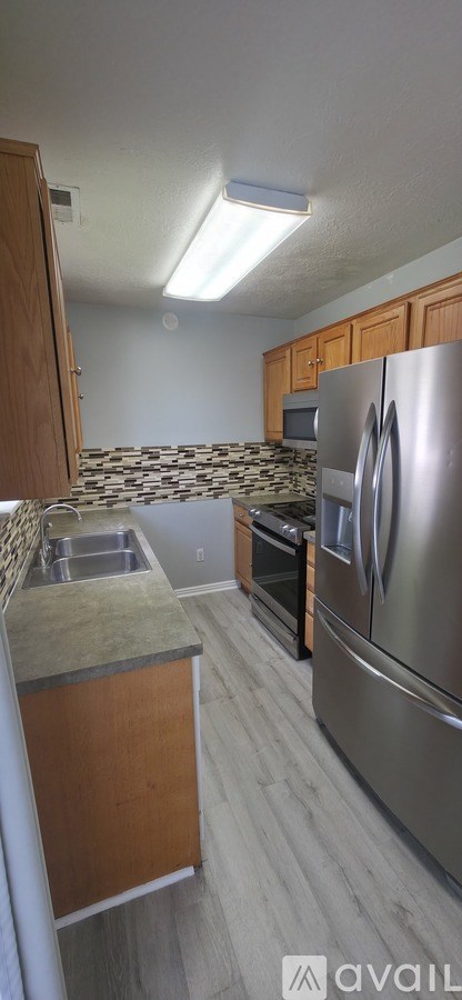 A kitchen with a stainless steel refrigerator and wooden cabinets.