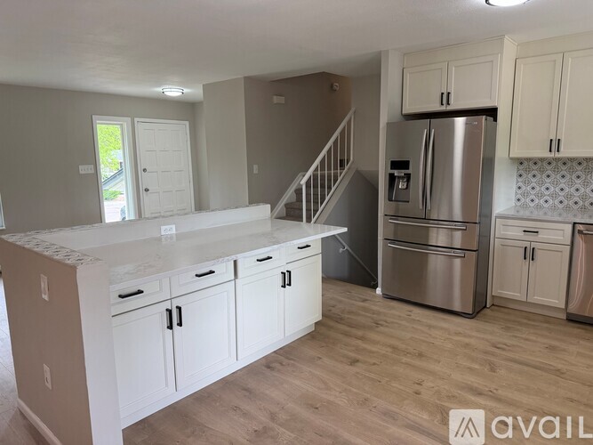 A kitchen with white cabinets and a stainless steel refrigerator.