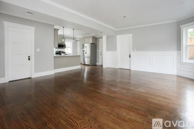 A spacious room with wooden flooring and white walls.