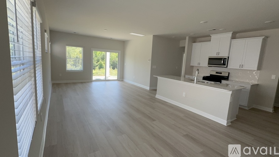 A spacious kitchen with white cabinets and a microwave above the island.