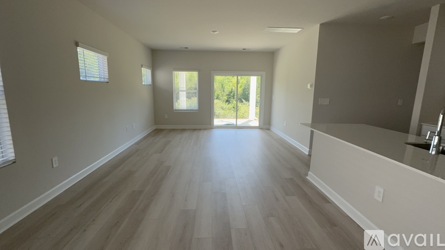 A spacious room with wooden flooring and a large window.