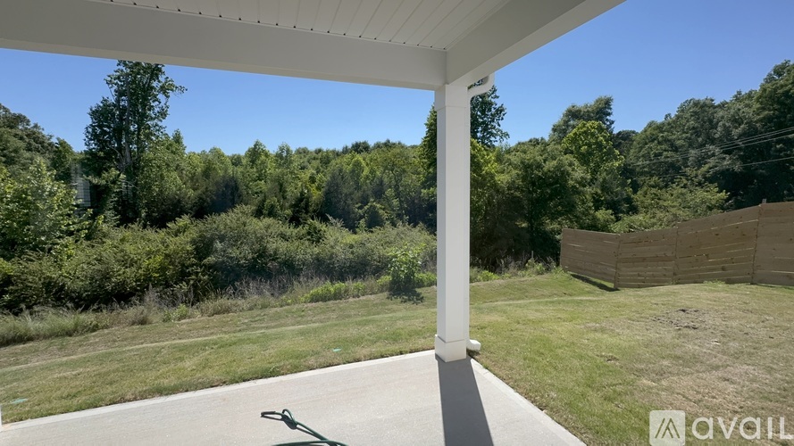 A white column stands on a concrete slab with a grassy area and trees in the background.