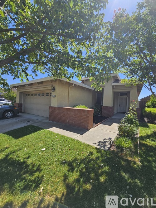 A house with a garage and a tree in front.