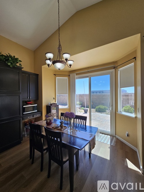 A dining room with a table set for four and a chandelier hanging from the ceiling.