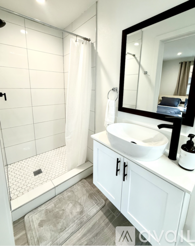 A white bathroom with a sink, mirror, and shower.