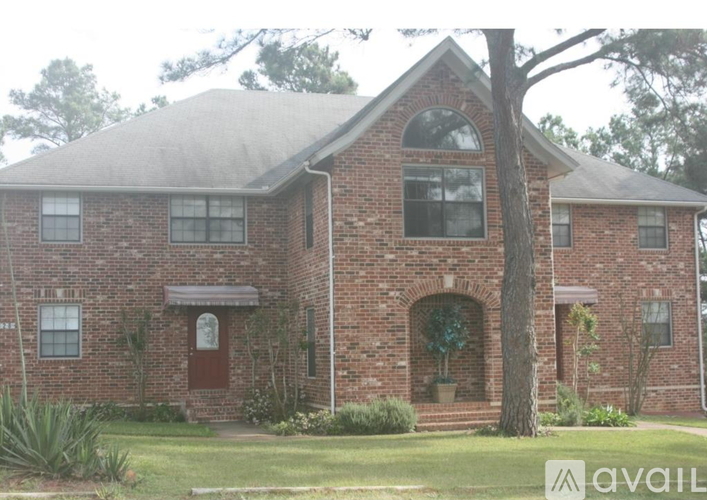 A brick house with a tree in front.