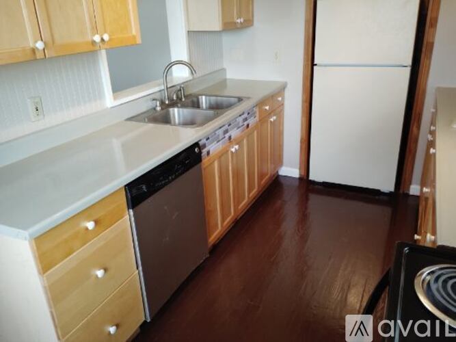 A kitchen with wooden cabinets and a black dishwasher.