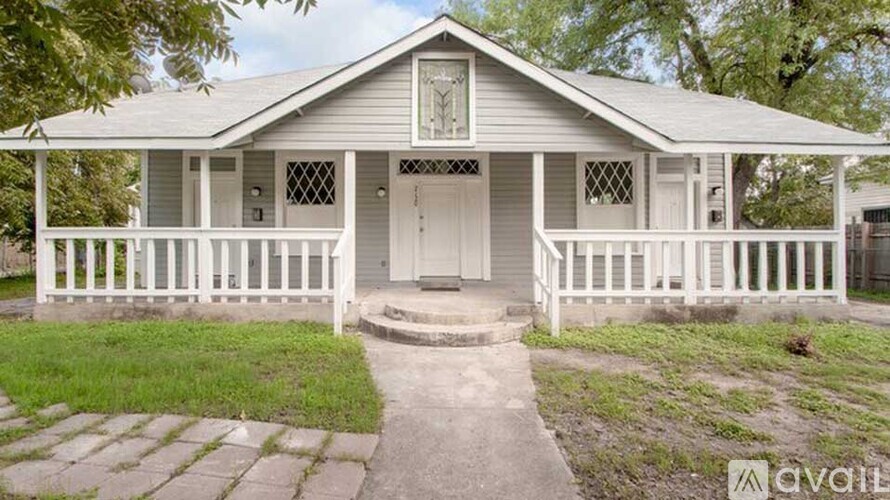 A small house with a porch and a white picket fence.
