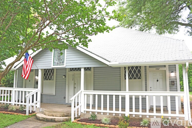 A small house with a porch and an American flag hanging on the front.