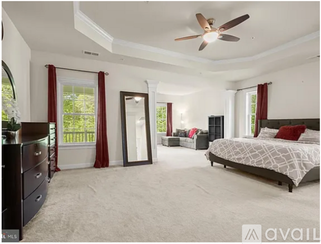 A bedroom with a large bed, a dresser, and a ceiling fan.