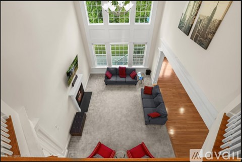 A living room with a grey rug and a grey couch with red pillows.