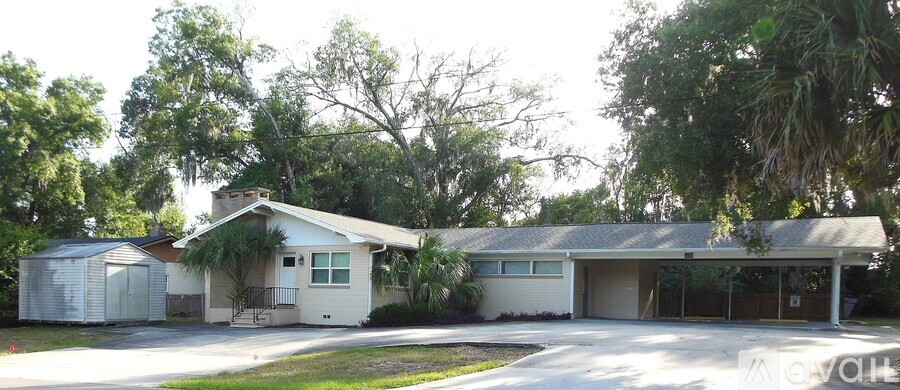 A house with a white garage door is surrounded by trees.