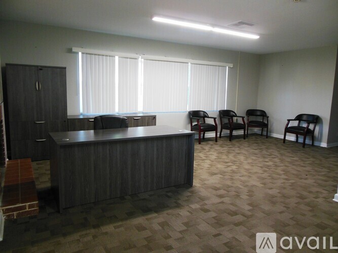 A room with a desk, chairs and a window.