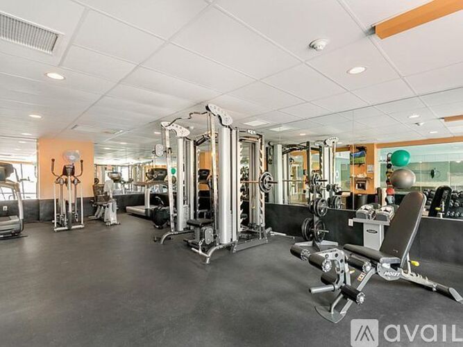 A gym with a variety of equipment including a squat rack, bench press, and a mirror.