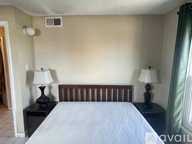A bedroom with a bed, two lamps, and a nightstand.