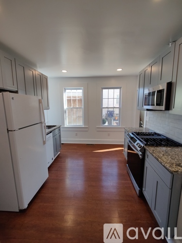 A kitchen with white appliances and wooden floors.