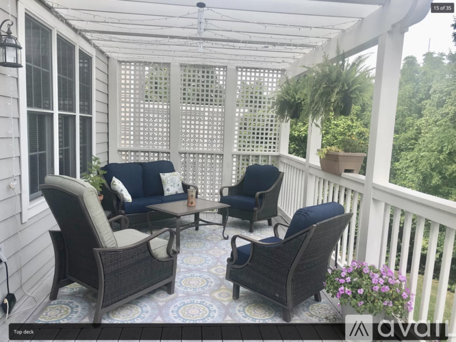 A patio with a white railing and a white pergola with a lattice top.