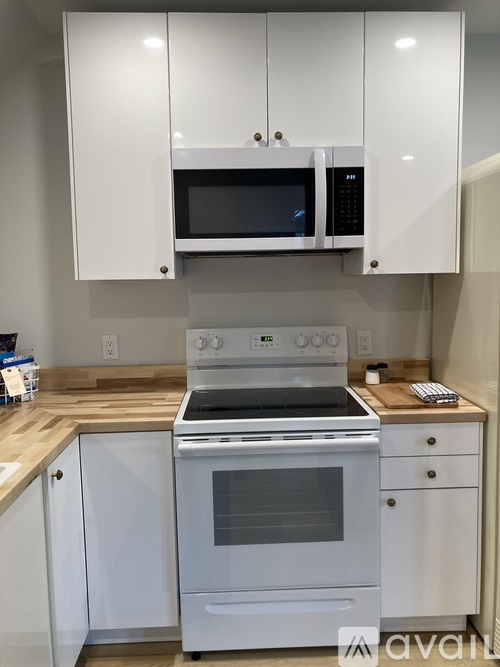 A white kitchen with a stove and microwave.