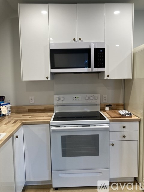 A white kitchen with a stove and microwave.