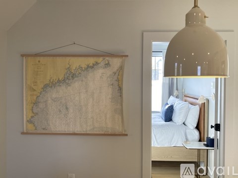 A bedroom with a large map hanging on the wall and a bed with white sheets and blue pillows.