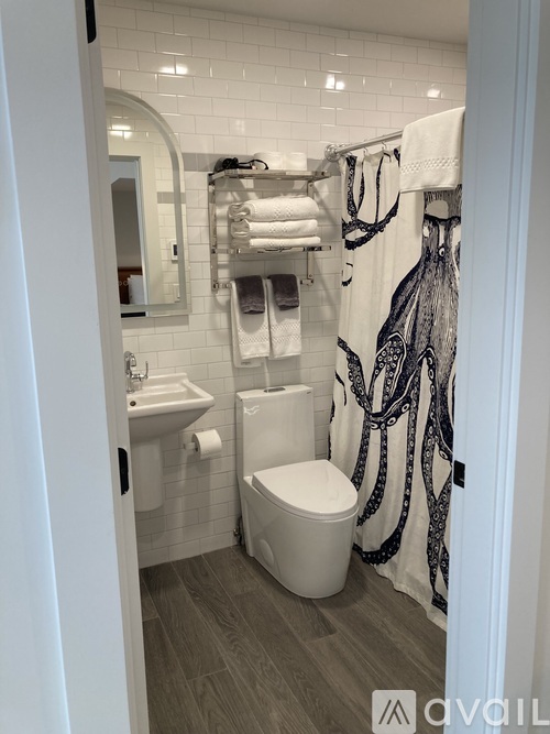 A bathroom with a toilet, sink, and a shower curtain with an octopus design.