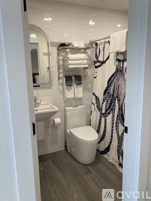 A bathroom with a toilet, sink, and a shower curtain with an octopus design.