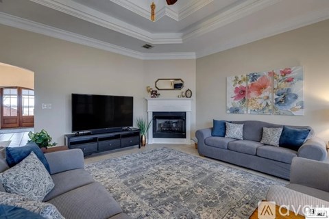 A living room with a grey couch, a fireplace, and a painting on the wall.