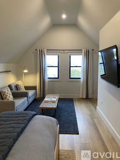 A living room with a grey couch and a black and white striped bedspread.