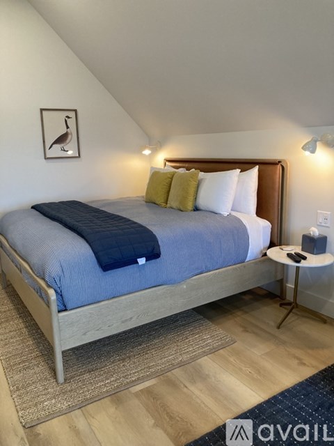 A bedroom with a bed, a small table, and a picture of a bird on the wall.
