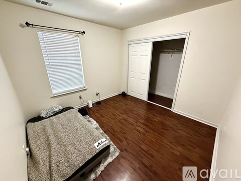 A bedroom with a bed and a window with blinds.