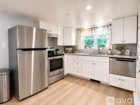 A kitchen with a stainless steel refrigerator and white cabinets.