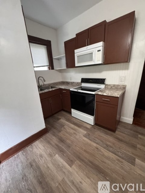 A kitchen with brown cabinets and a white microwave above the stove.