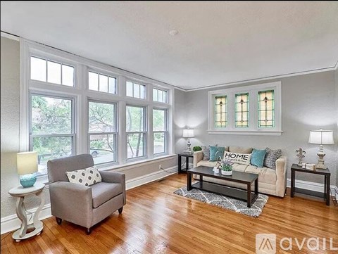 A living room with a grey sofa, a grey armchair, a white side table and a wooden floor.