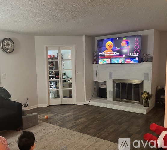 A living room with a television on the wall and a fireplace below it.