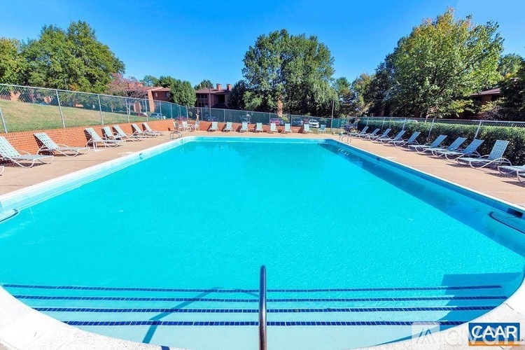 A large outdoor swimming pool surrounded by lounge chairs and trees.