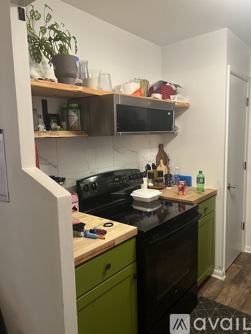 A kitchen with green cabinets and black appliances.