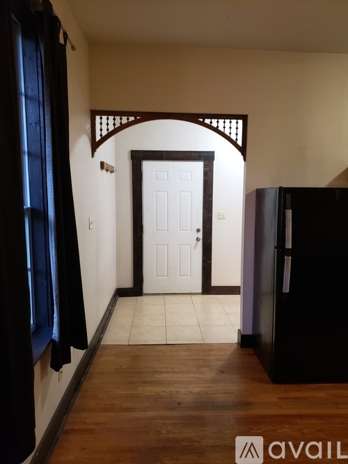 A hallway with a white door and a black refrigerator.