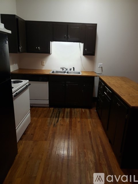 A kitchen with black cabinets and a wooden floor.