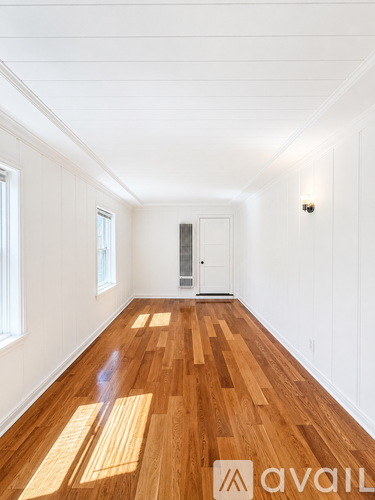 A hallway with wooden floors and white walls.