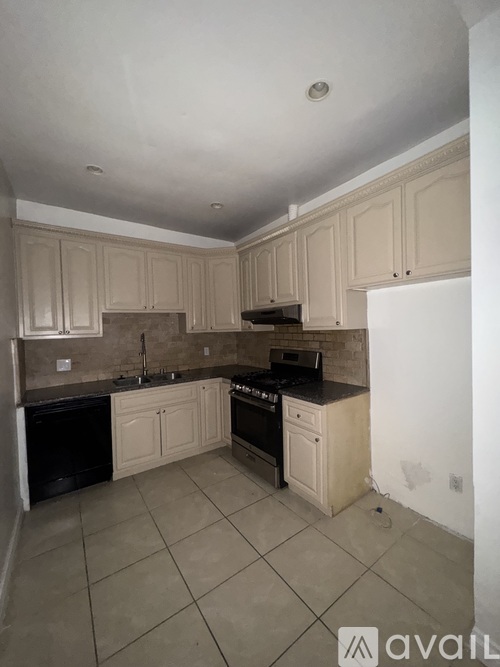 A kitchen with beige cabinets and black appliances.
