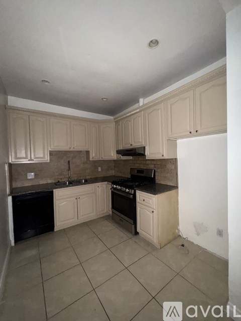 A kitchen with beige cabinets and black appliances.