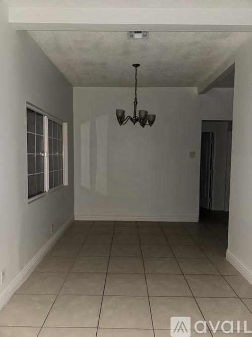 A room with a chandelier and tiled flooring.