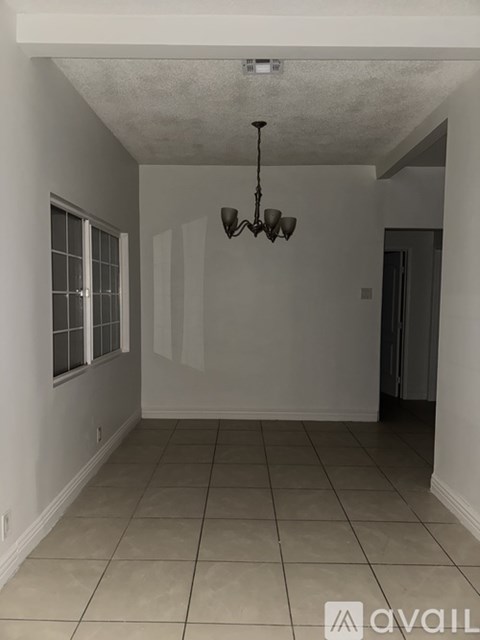 A room with a chandelier and tiled flooring.