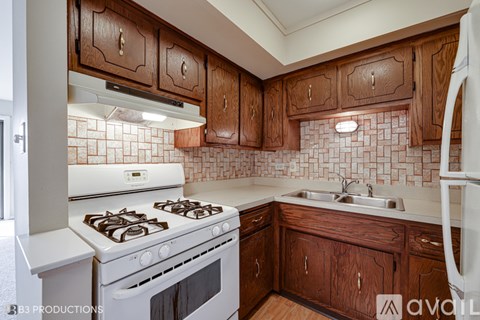 A kitchen with wooden cabinets and a white stove top oven.