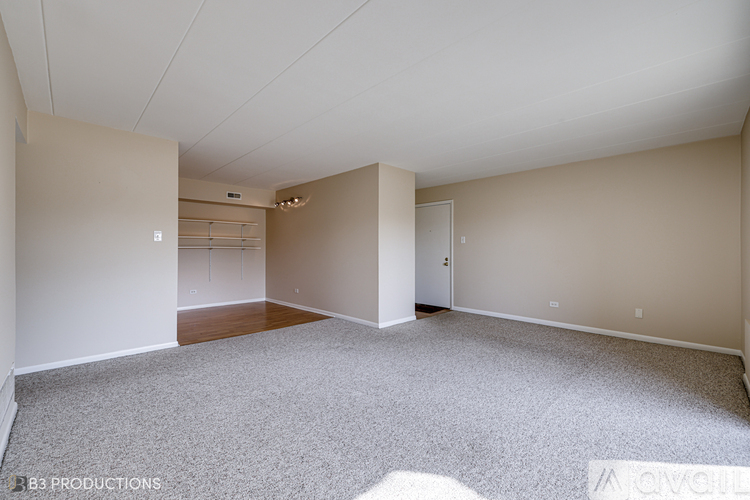 A spacious room with a carpeted floor and white walls.